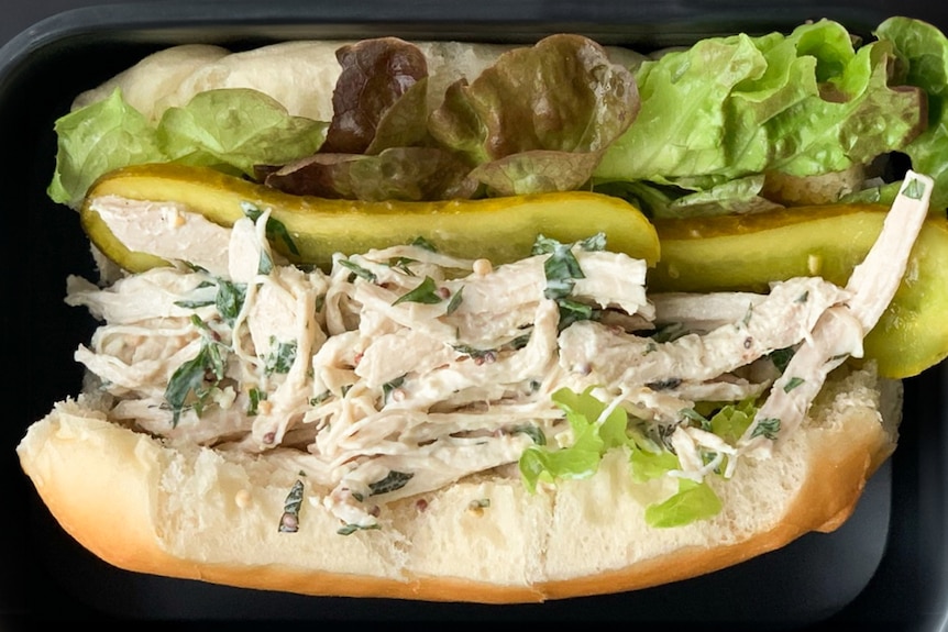 A soft white roll with a poached chicken filling, pickles and lettuce.
