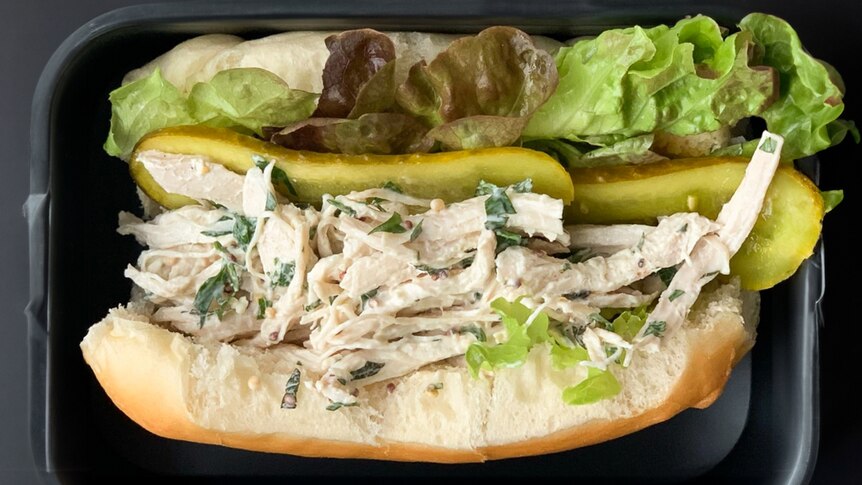 A soft white roll with a poached chicken filling, pickles and lettuce.