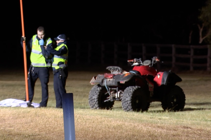 Two police officers standing near a quad bike.