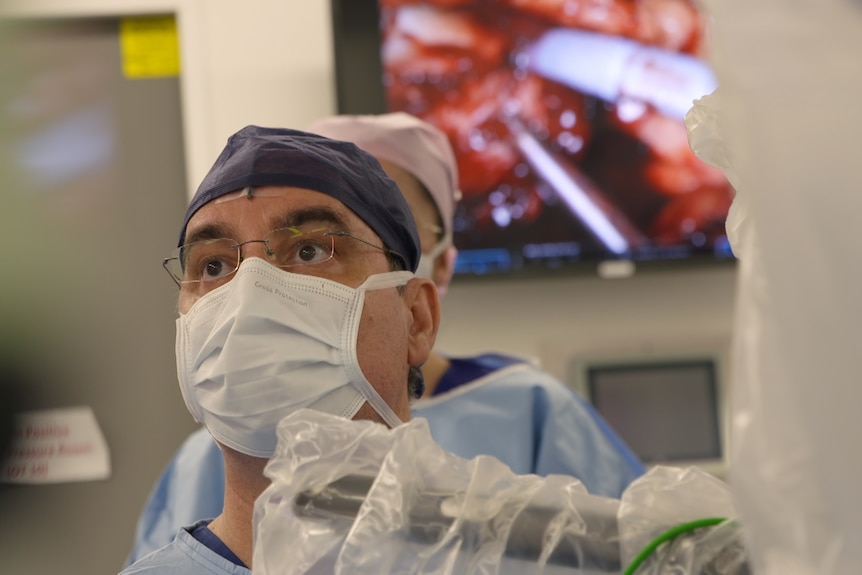 Dr staring intensely while vision of operation is in background