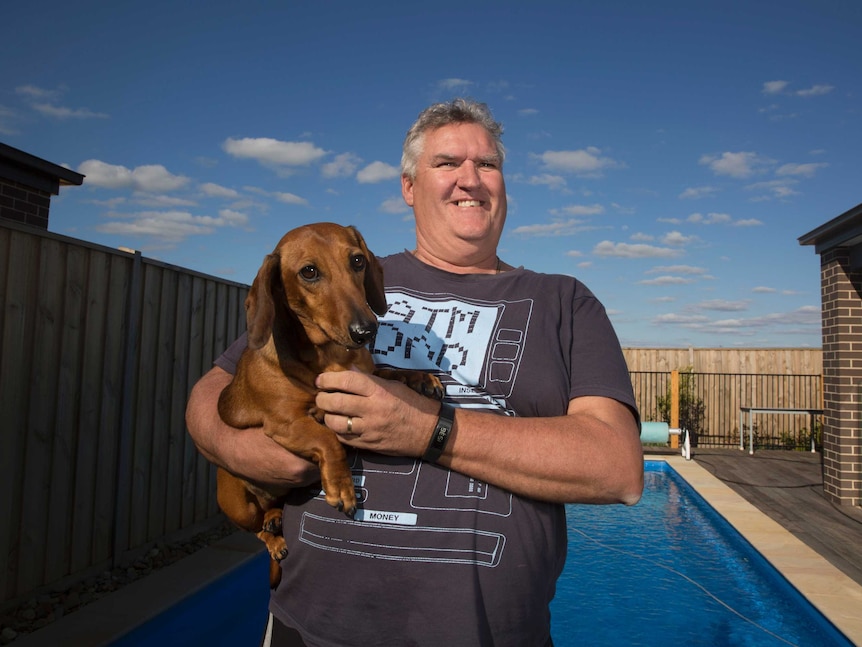 Craig Bolten standing in front of his pool with his dashund