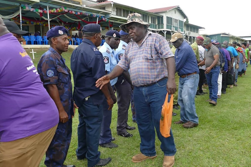 Former Bougainville Revolutionary Army fighters shake hands with Papua New Guinea policemen at a reconciliation ceremony.