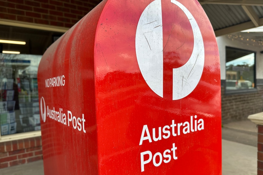 An Australia Post red post box outside a post office.