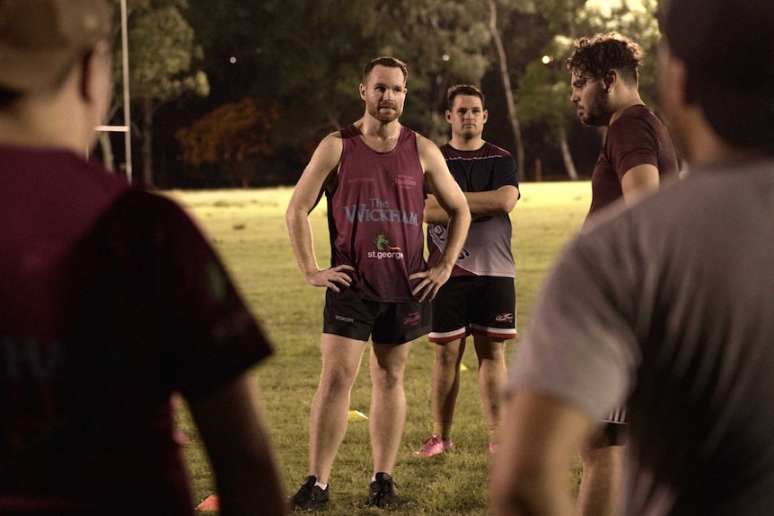 Men stand around on a sports field.