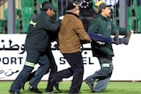 Medical personnel carry an injured fan across the pitch during clashes between Al-Ahly and Al-Masry.