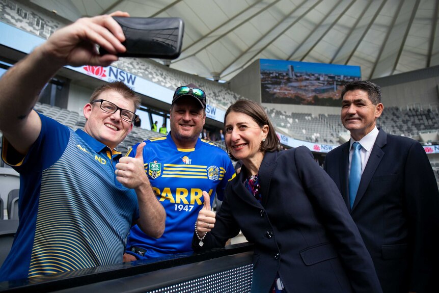 Gladys Berejiklian poses for a selfie with some football fans.