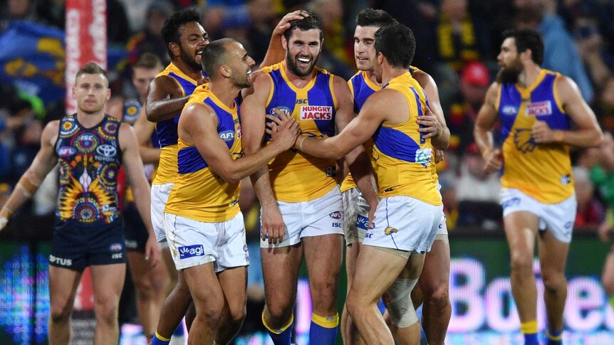 A group of Eagles players smile as they walk back after a goal against the Crows.