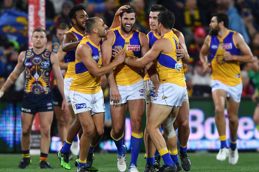 A group of Eagles players smile as they walk back after a goal against the Crows.