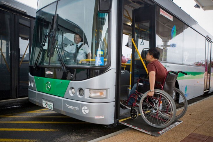 A wheelchair user boards a bus via a ramp.