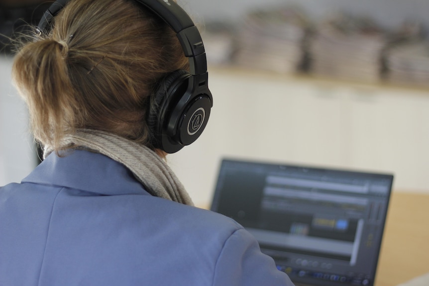 We look over a woman's shoulder as she works on a computer. 