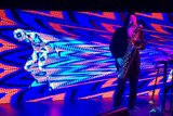 A saxophonist with taped up eyes performs in front of a colourful LED screen