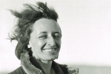 A black-and-white image of a smiling woman dressed in a warm coat standing in outback South Australia.