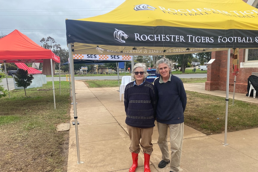 Two people standing together outside a marquee.