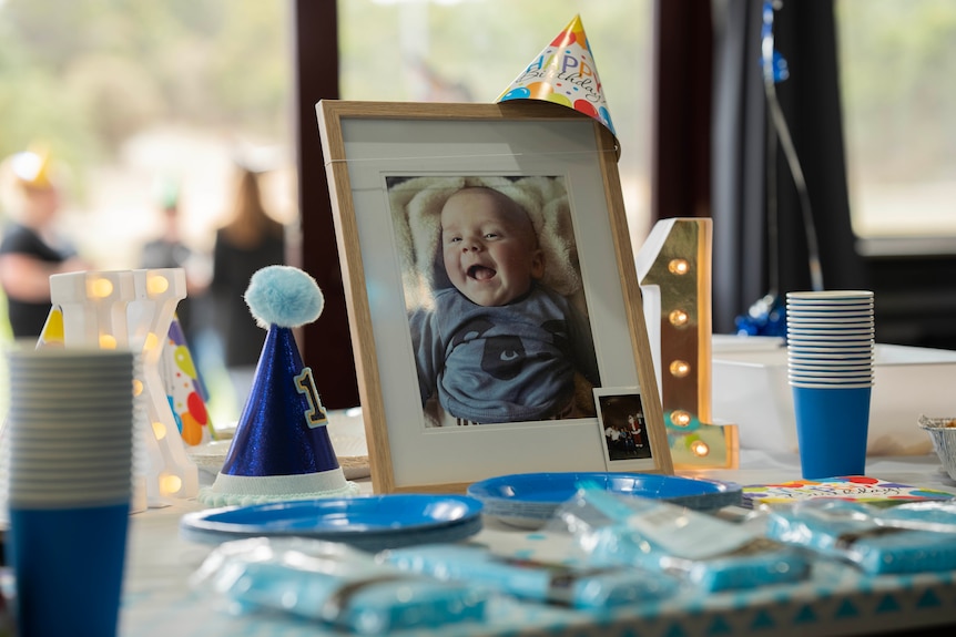 A picture of a baby on a table at a birthday party.