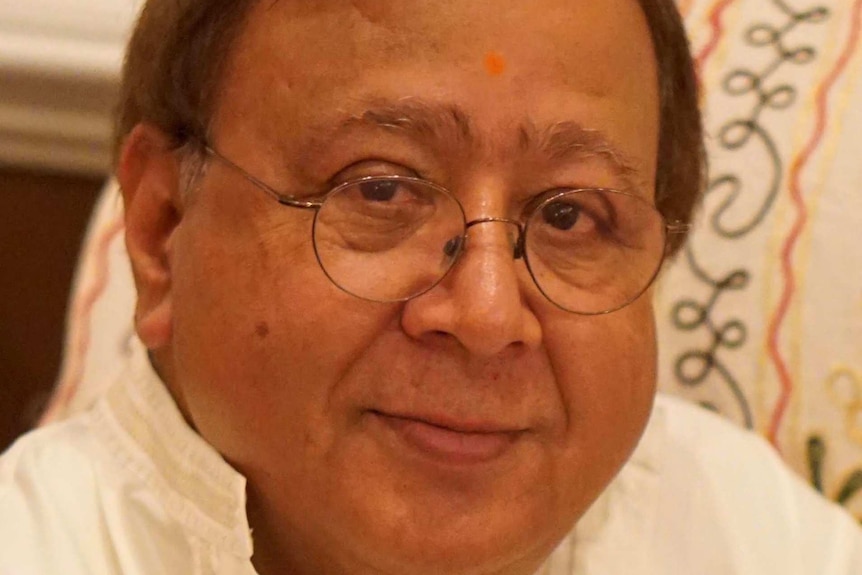 Dark-haired man with round glasses wearing white button-up shirt