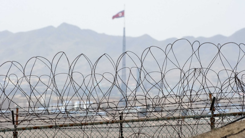 A file photo taken on March 25, 2012 shows a North Korean flag behind the barbed wire of the Demilitarized Zone