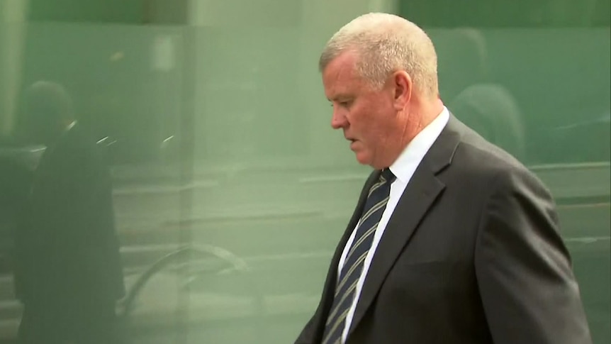 A man in a suit in front of a glass wall