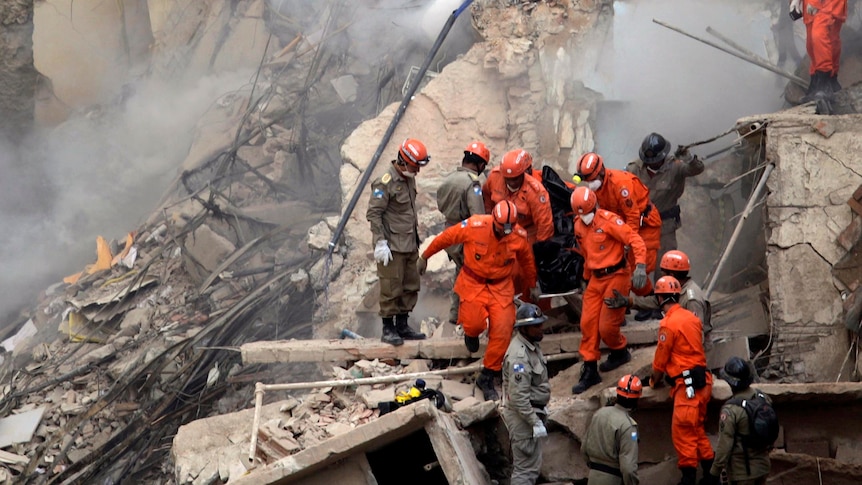 Firefighters carry the body of a victim through the debris of a collapsed building in Rio.