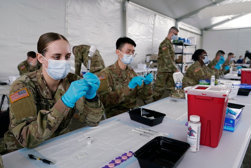 Army health specialists fill syringes with the Pfizer COVID-19 vaccine in Miami.