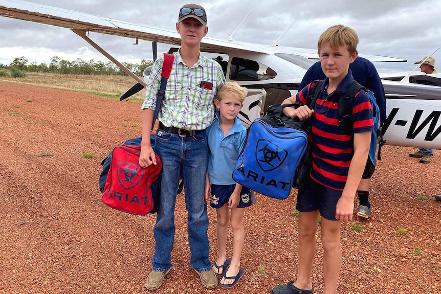 A mother with two sons in front of a small plane on an outback landing strip
