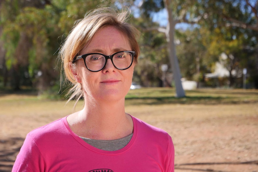 Women in glasses in pink shirt standing in front of trees