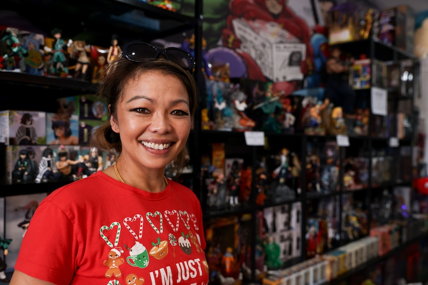 A woman smiles looking straight at the camera. She's wearing a red Christmas T-shirt and sunglasses.
