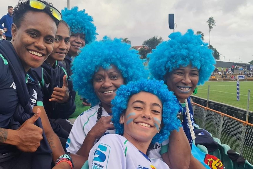 Naomi Roberts (centre) smiles with other "Blue Wigger" fans and Fijiana Drua players.