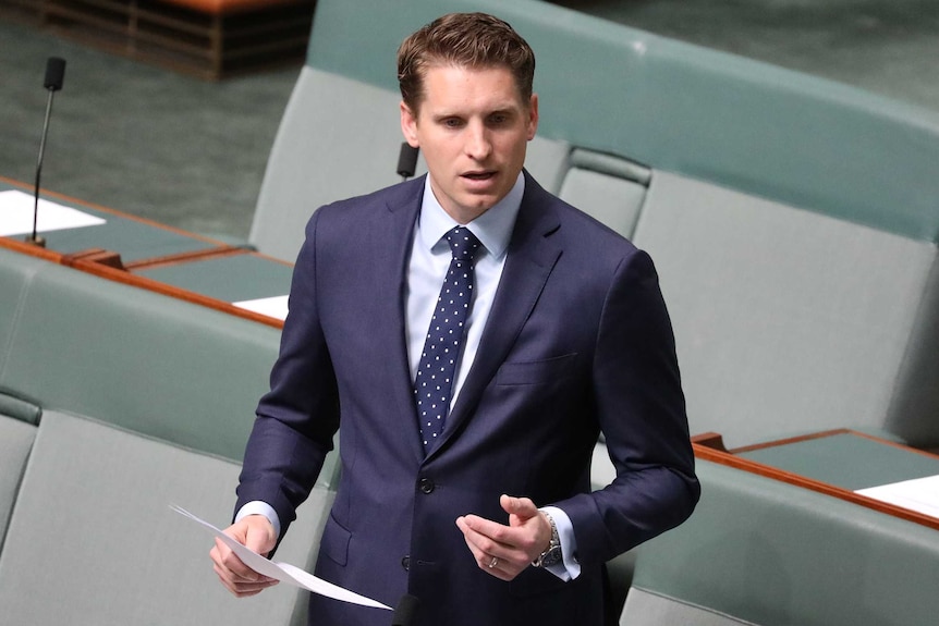 Andrew Hastie stands in the House of Representatives. He is holding a piece of paper and gesturing with his other hand.