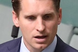 Andrew Hastie stands in the House of Representatives. He is holding a piece of paper and gesturing with his other hand