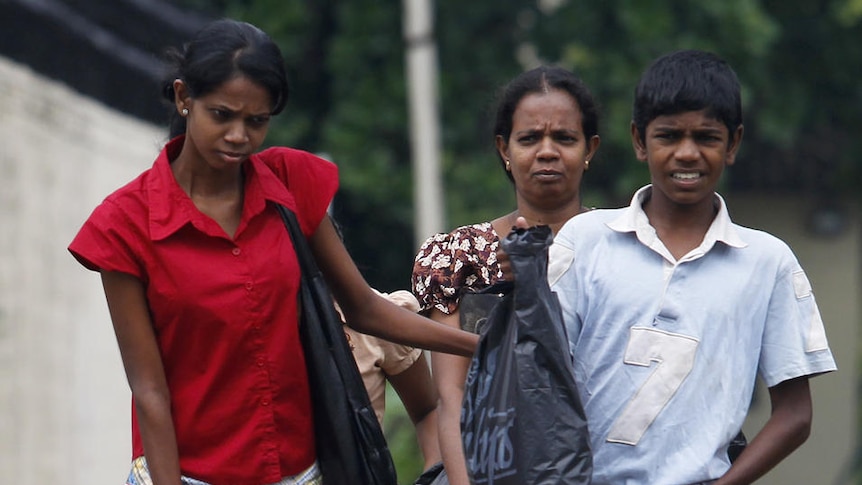 A Sri Lankan family wades through floodwaters