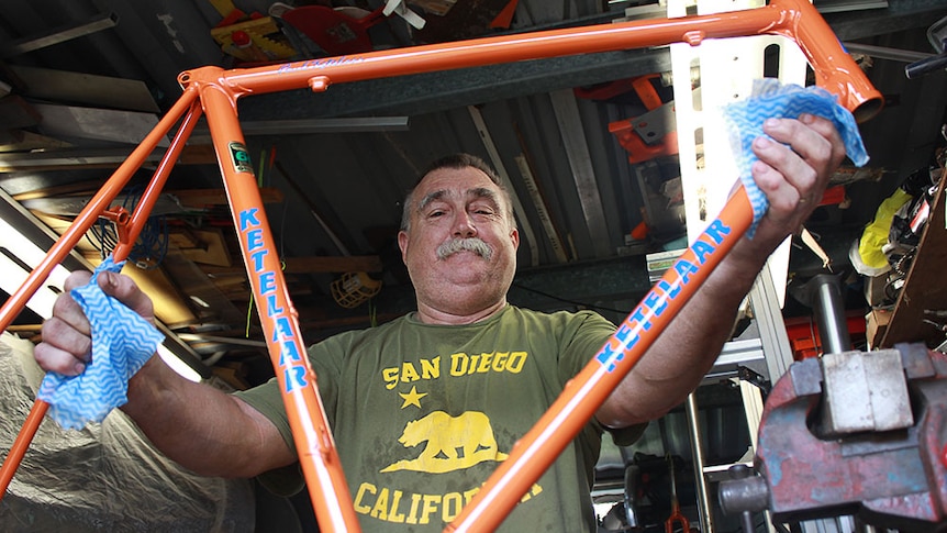 Paul Ketelaar holding an orange handmade bicycle.