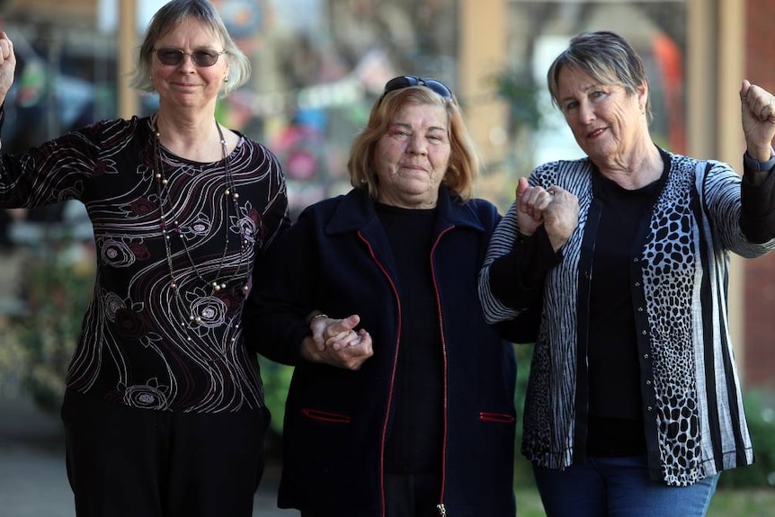 Three women link arms.