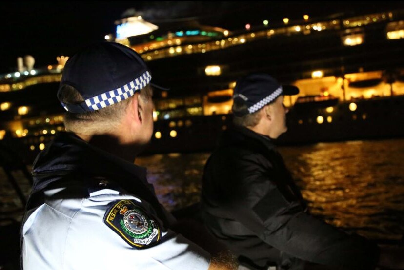 Two policemen on the harbour in front of a cruise ship.