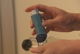Salbutamol inhaler being held in  a hand.