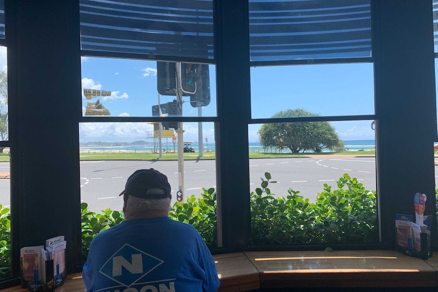 Hotel patron sitting at pub window gazing out to Kirra Beach.