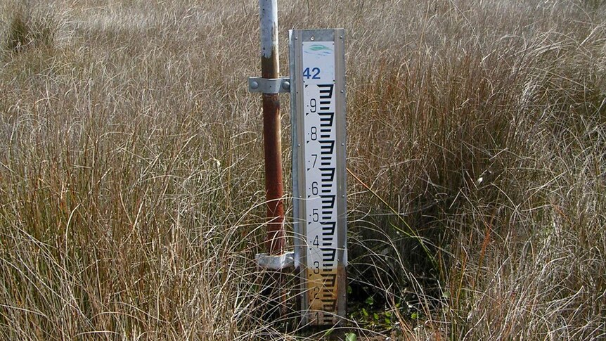 A water gauge on a dry area of wetland showing water only up to the 1 level.