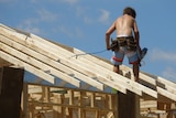 A construction worker stands on a roof on a construction site
