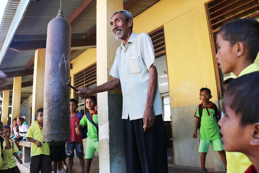 Principal of Dili's Fomento Primary School rings the bell to end lunch recess.