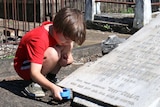 Jack Chenoweth, 7, cleans a headstone with a scrubbing brush.