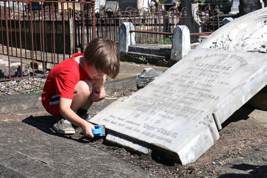 Jack Chenoweth, 7, cleans a headstone with a scrubbing brush.