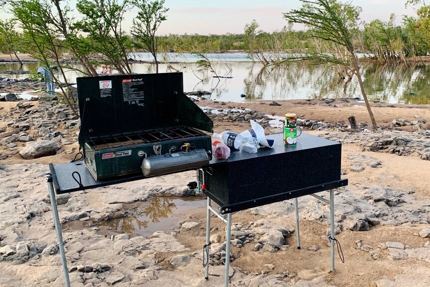 A camp kitchen is set up near a waterway.