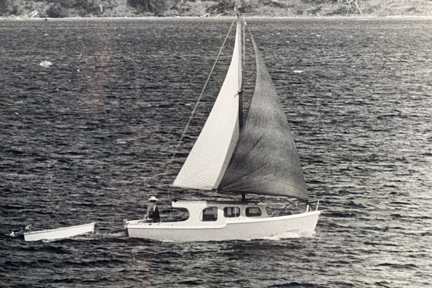 a black and white photo of a little boat in sail on a river