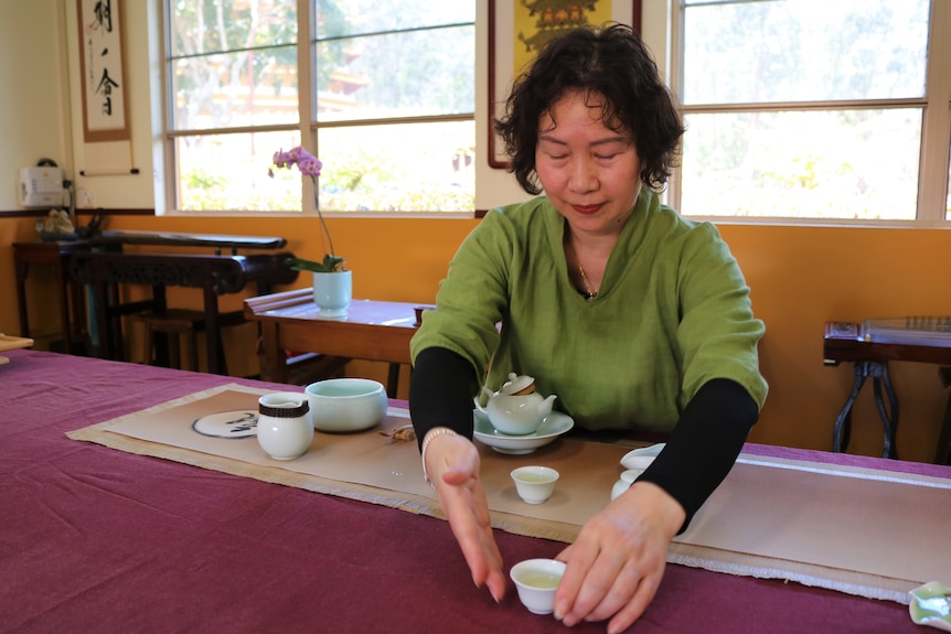 A woman holds a tea cup as part of a special Chinese tea ceremony at a Buddhist temple.