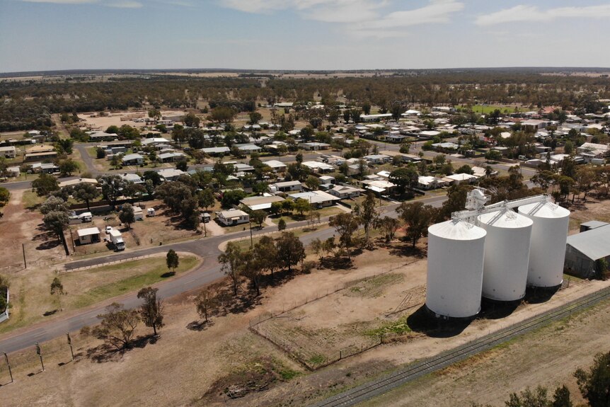 an aerial shot of a small town with three large grain silos in the corner