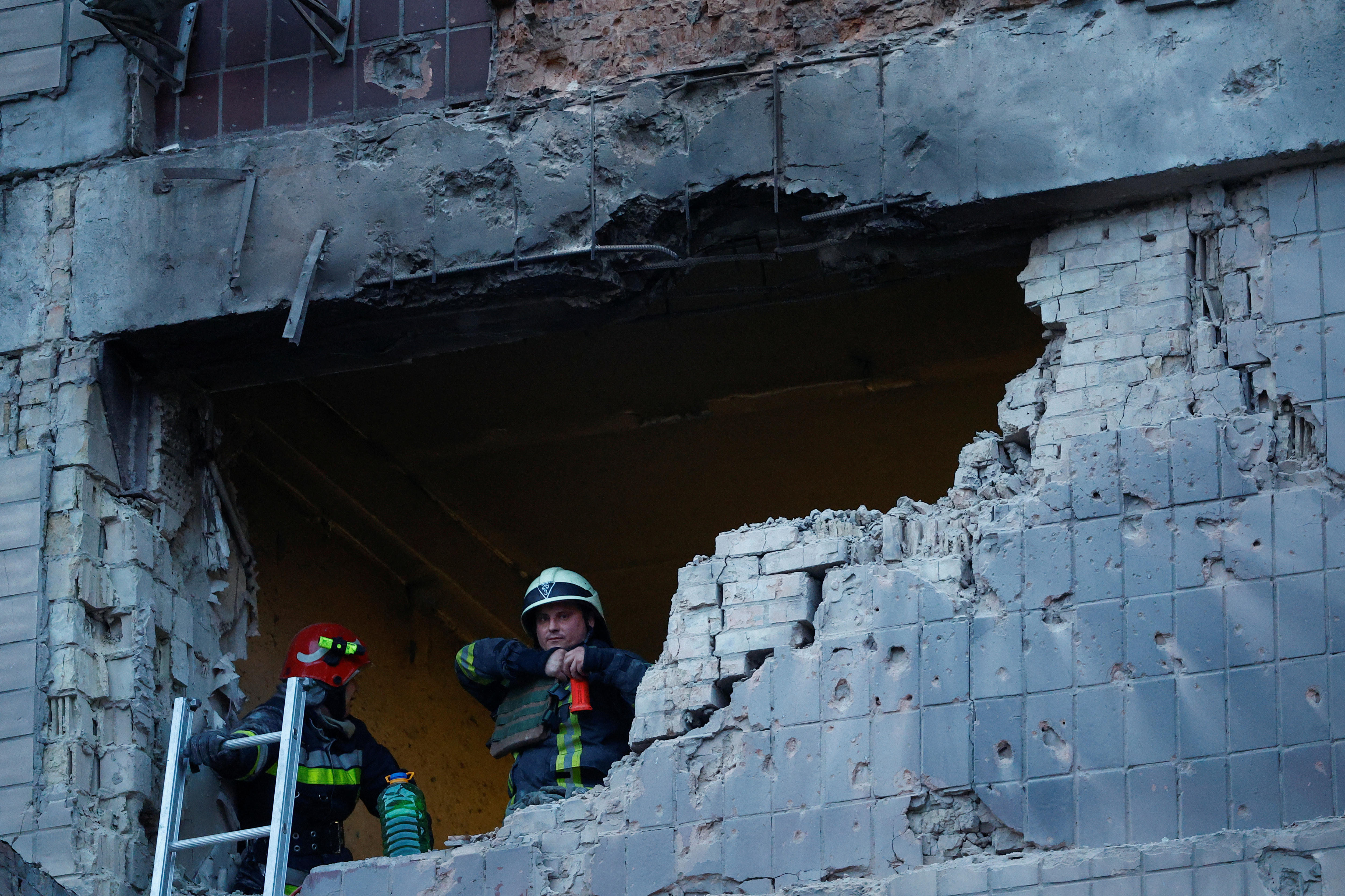 Rescuers look out a large hole blown out from a brick building by a suicide drone. 