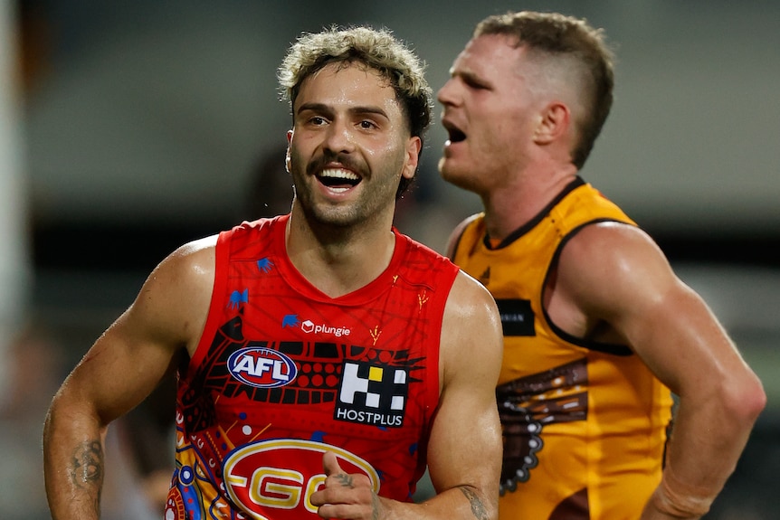 A Gold Coast Suns AFL player smiles after a goal was scored against Hawthorn.
