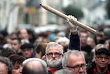 A man at a rally holds a giant pencil in the air