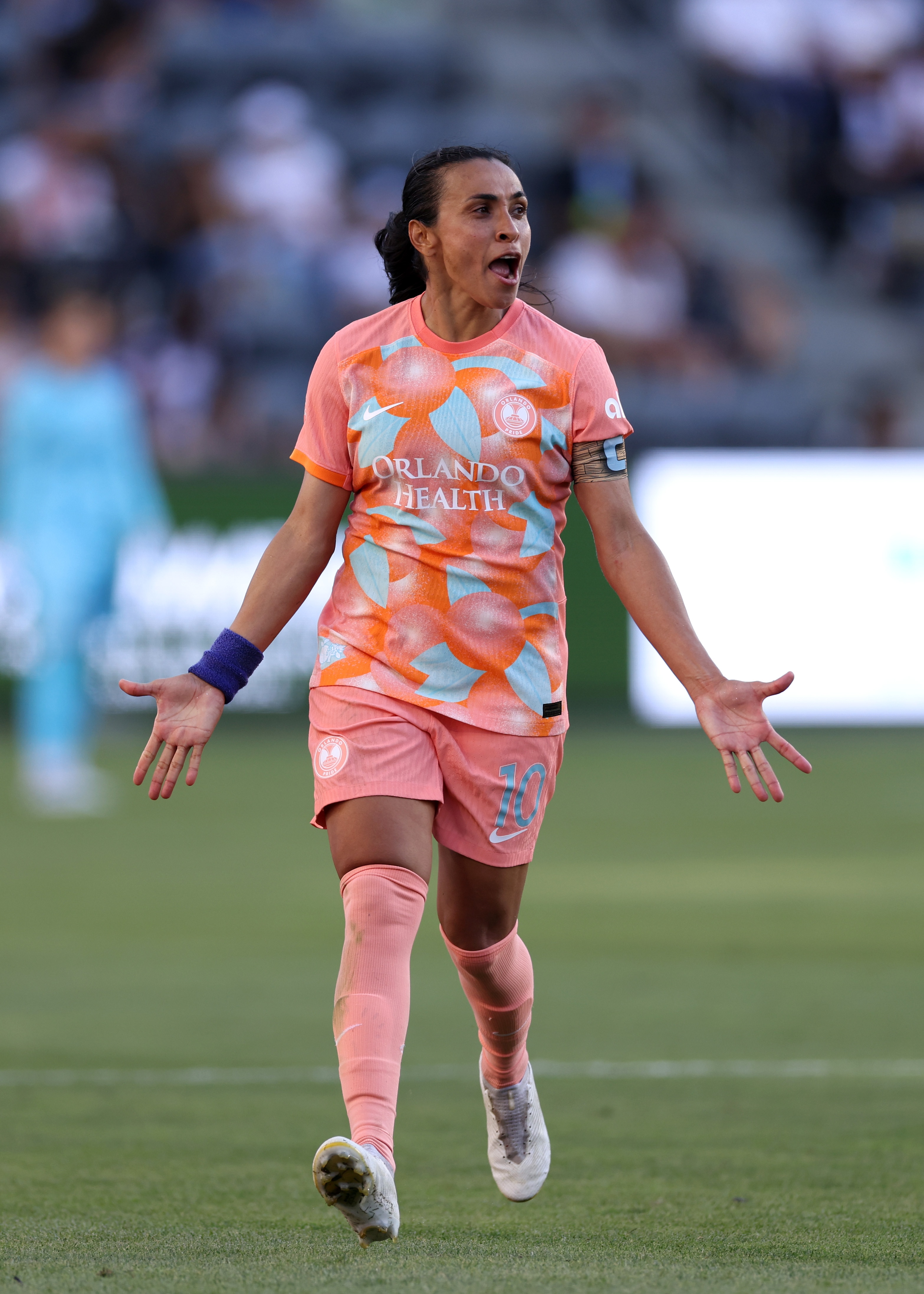 A woman soccer player wearing orange and blue runs during a game