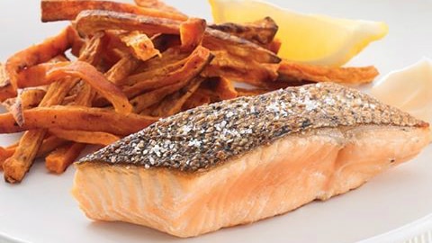 piece of cooked salmon on a plate with sweet potato chips