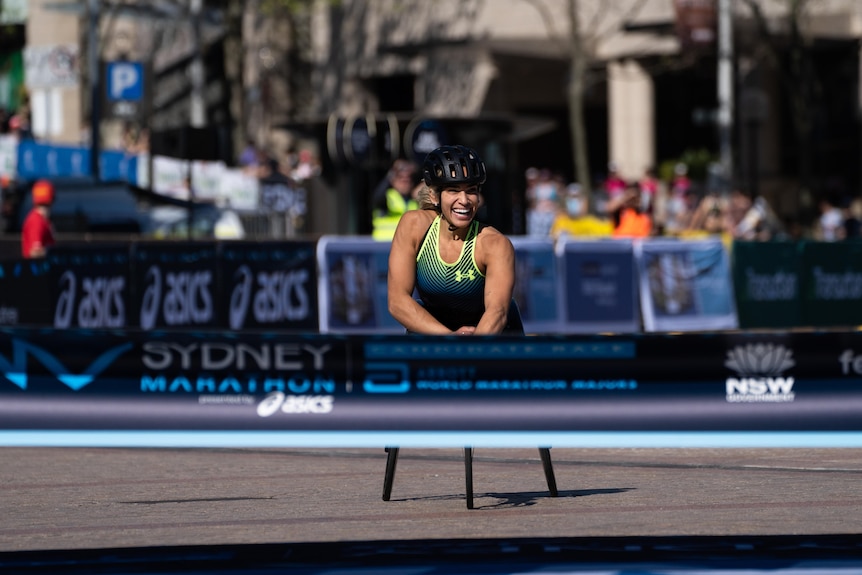 wheelchair athlete smiles as she crosses the finish line ribbon
